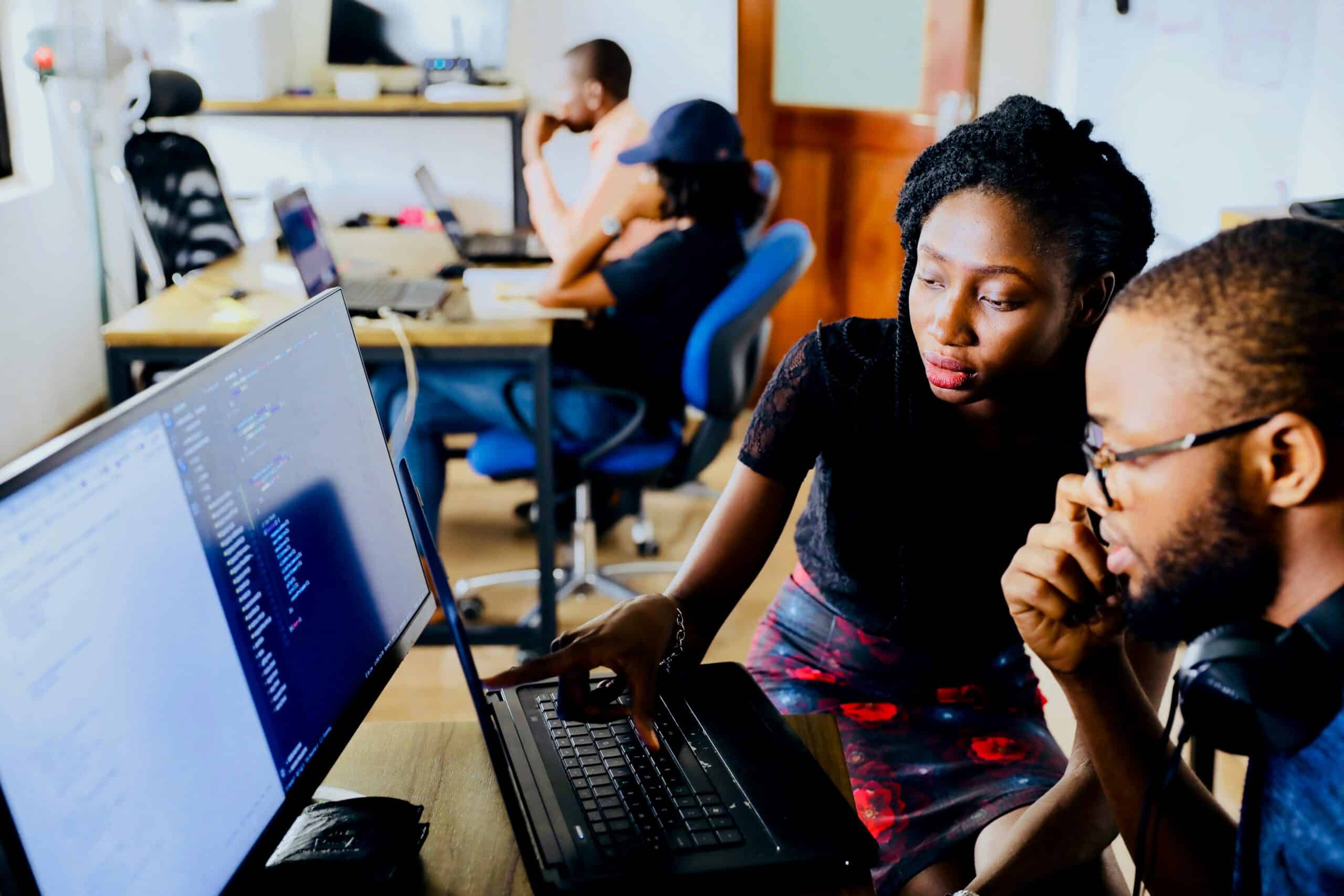 Woman and man sitting in front of desktop computer woman teaching man how to uise