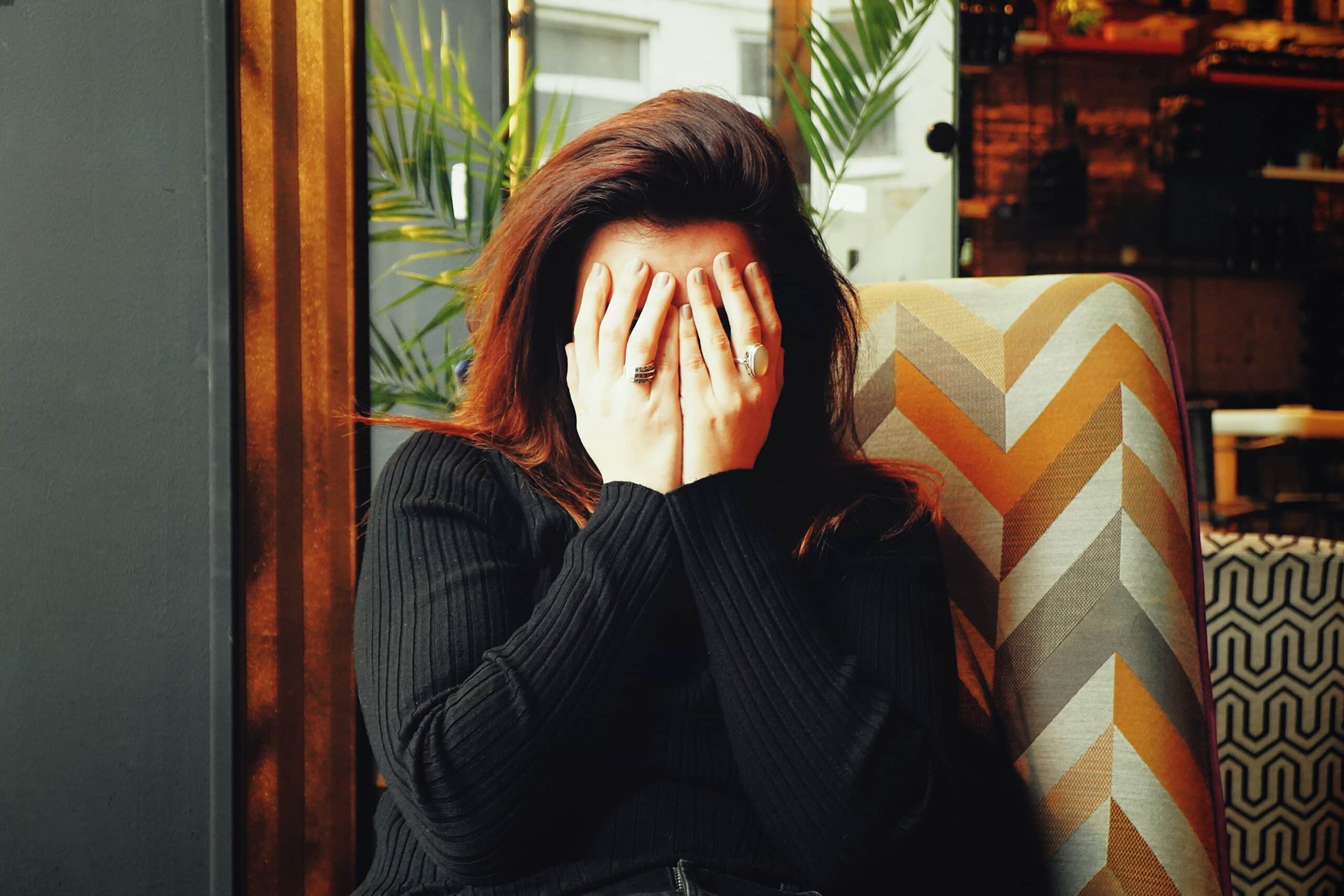 woman in black longsleeve shirt covering her face